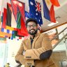 Edward Moses standing under a display of international flags. 
